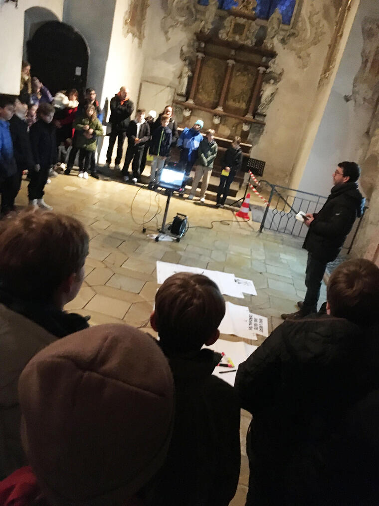 Kinder und Erwachsene stehen vor einem Altar an einer Station zum Thema "Durchhalten"