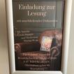 Ein Plakataufsteller mit einem Plakat für eine Lesung mit einem braunen Ledersessel