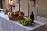Auf einem Tisch sind Brot, Wein, Trauben und ein Kerzenleuchter aufgebaut als Abendmahlsscene
