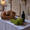 Ein Abendmahltisch, gestaltet mit einem Kerzenleuchter, einem Korb mit Brot, mit Weintrauben und einer Weinflasche