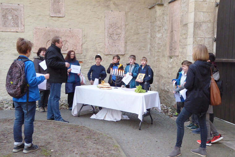 Kinder an einem Tisch mit Kerzenleuchter, Brot und Trauben