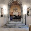 Blick durch einen Torbogen in einen Kapelle, dort sitzen Kinder auf dem Boden bei einer Andacht