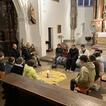 Kinder sitzen in einem Kreis auf Bänken in einem Kirchenraum