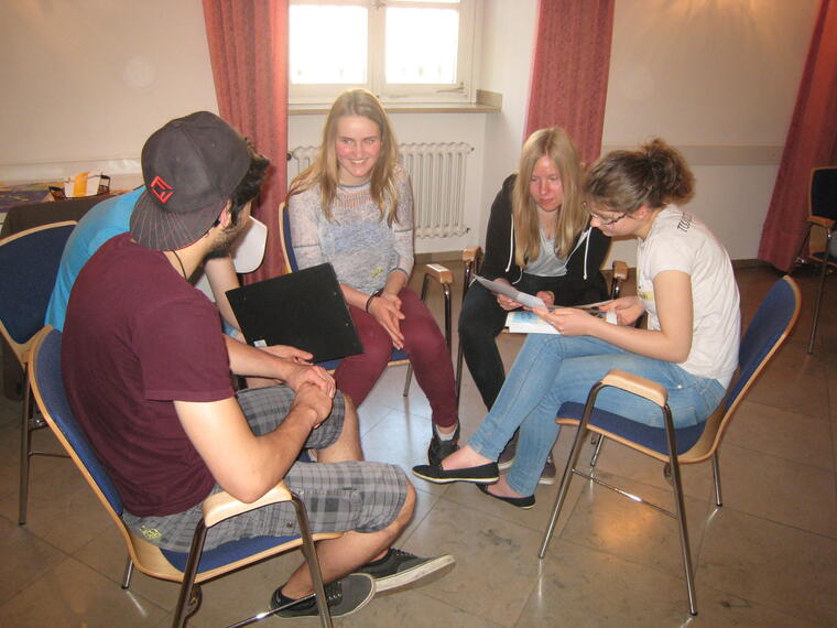Jugendliche sitzen in Kleingruppe und versuchen, ein Comic fertig zu schreiben.