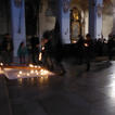 Firmkinder bringen Kerzen in einer Kirche nach vorne zum Kreuz