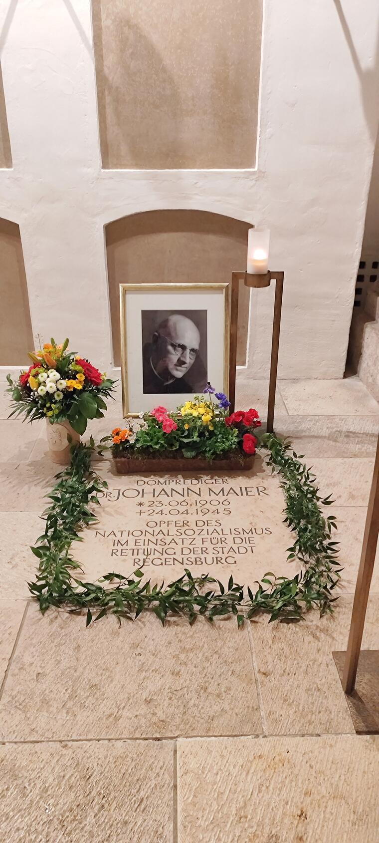Grablege mit Bild von Domprediger Dr. Johann Maier in der Krypta des Regensburger Doms, mit Blumen geschmückt.