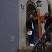 Zwei Schülerinnen haben ein großes Holzkreuz auf dem Treppenabsatz einer Kirche aufgestellt