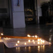 Brennende Kerzen stehen rund um ein am Boden liegendes Holzkreuz