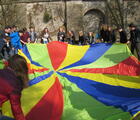 Jugendliche spielen mit einem bunten Fallschirm.