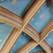Blick hinauf zu einem Ausschnitt eines Kreuzrippengewölbes, blau ausgemalt mit goldenen Sternen