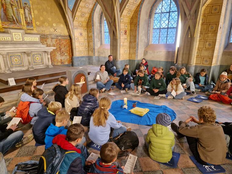 Ein Kindergottesdienst in einer Kapelle, alle sitzen am Boden