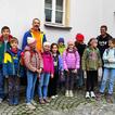 10 Kinder und 2 Erwachsene stehen vor einem Haus.