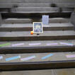 Auf Treppenstufen sind Bild und Textstreifen ausgelegt für eine Firmkreuzwegstation