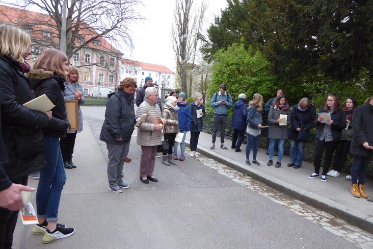 Gruppen von jüngeren und älteren Menschen stehen auf der Straße mit Kerzen in der Hand und folgen einer Kreuzwegststation